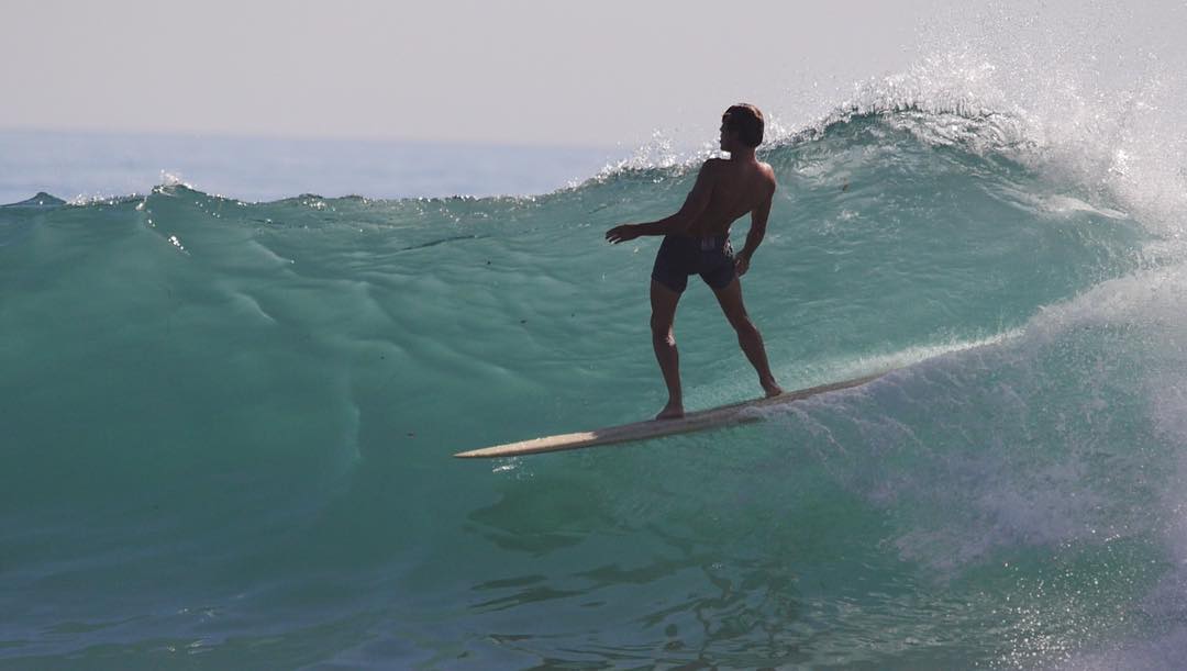 Person surfing on a wave in clear blue water