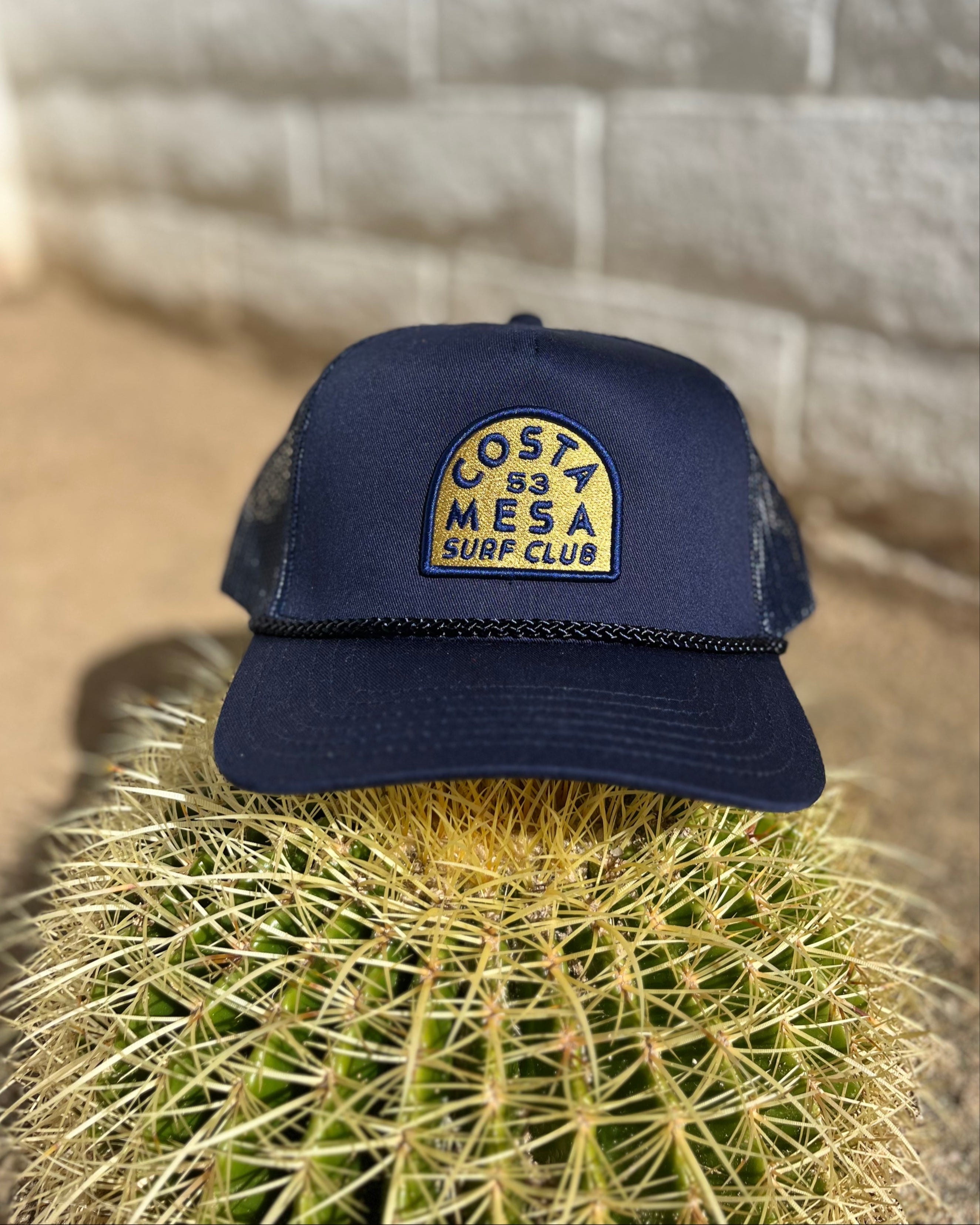 Costa Mesa Surf Club Trucker Hat Sitting On a Cactus