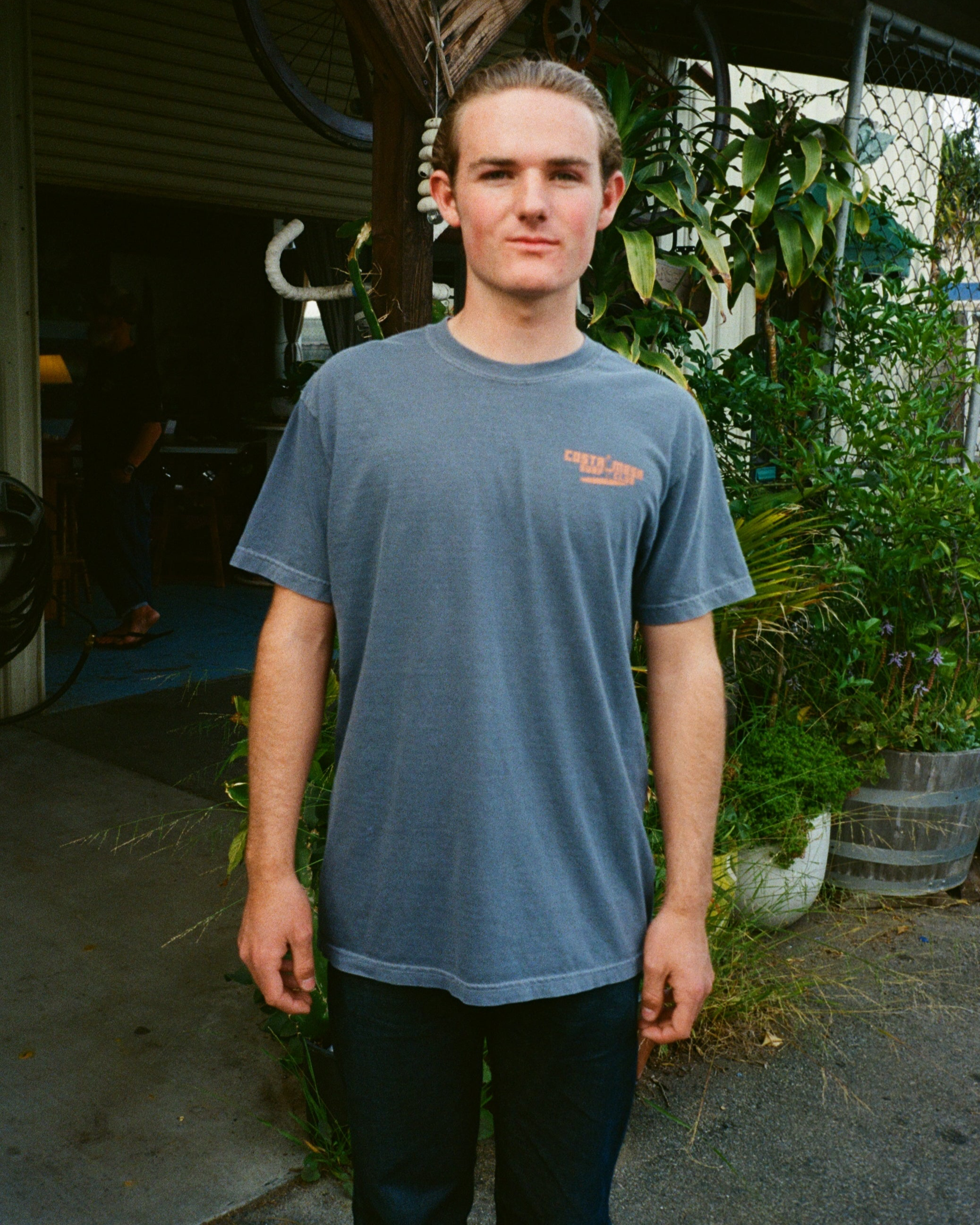 Person wearing a blue t-shirt with a logo in an outdoor setting