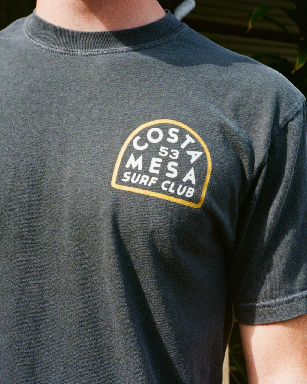 Black t-shirt with 'Costa Mesa Surf Club' logo on a person wearing it.