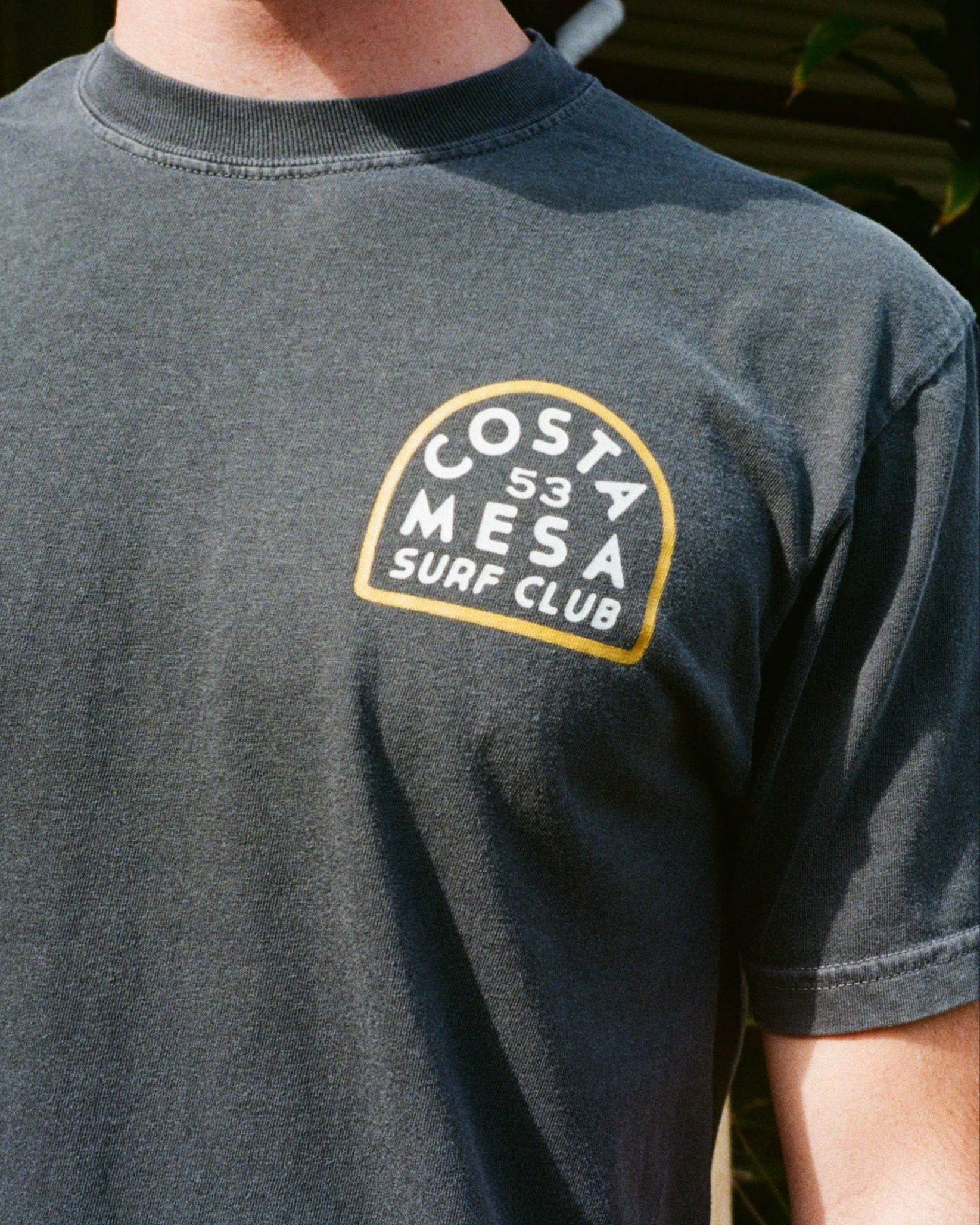 Black t-shirt with 'Costa Mesa Surf Club' logo on a person wearing it.