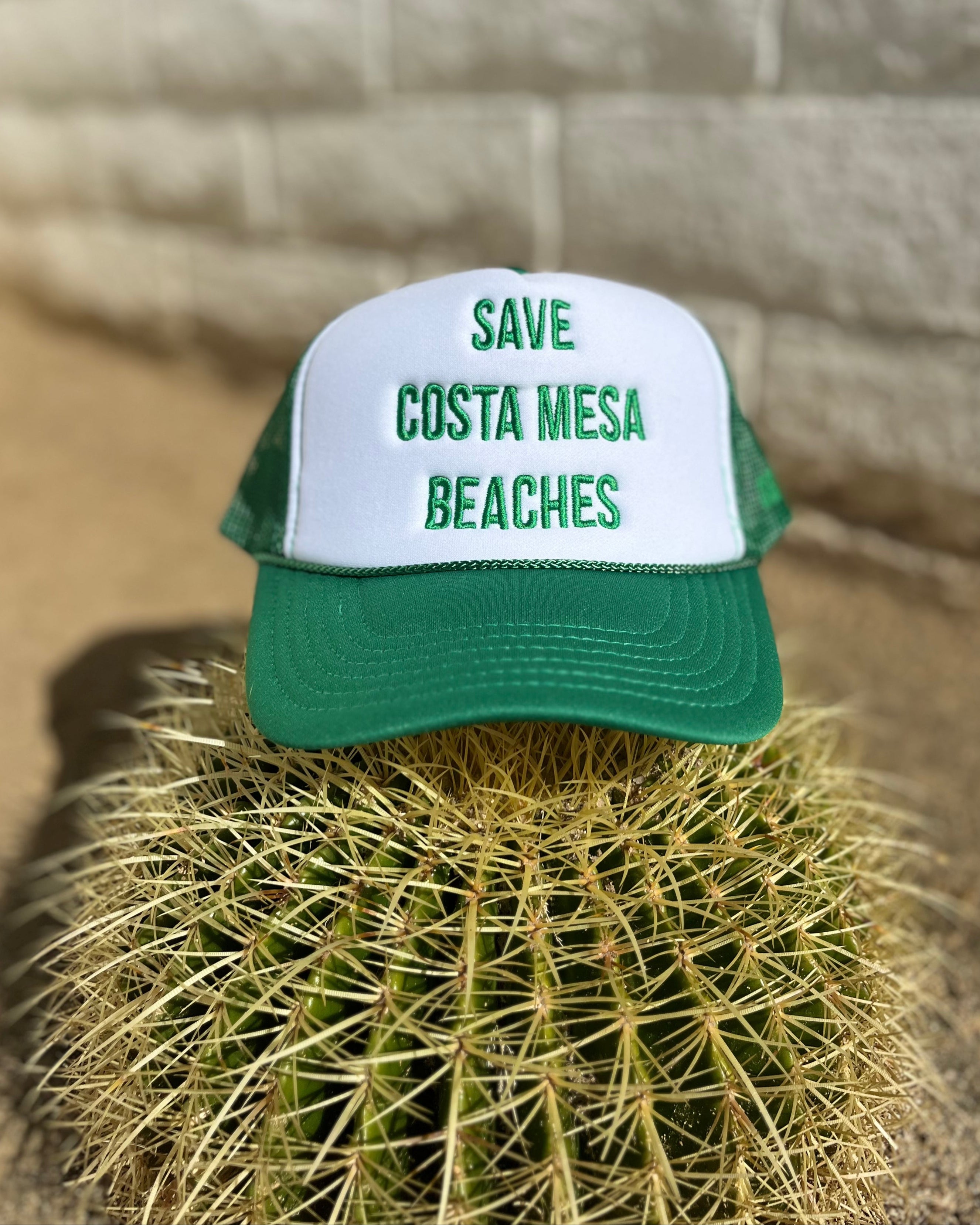 Green and white cap with 'Save Costa Mesa Beaches' text on a cactus plant.